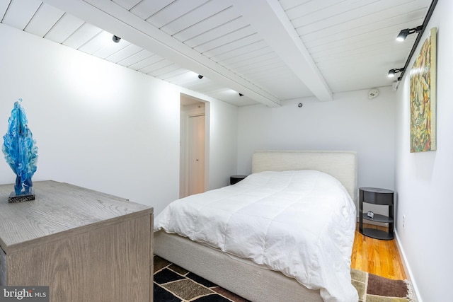 bedroom with beam ceiling, wooden ceiling, baseboards, and wood finished floors