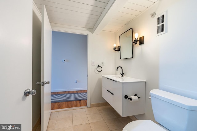 bathroom featuring vanity, visible vents, tile patterned flooring, beamed ceiling, and toilet