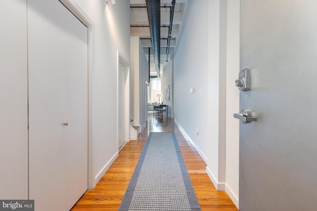 corridor with light wood-style floors and baseboards