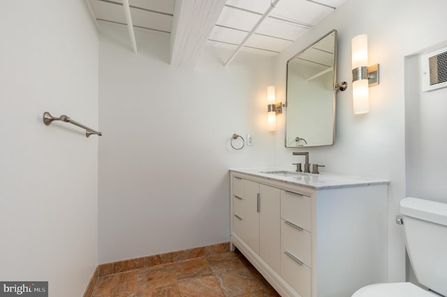 bathroom with toilet, vanity, and baseboards