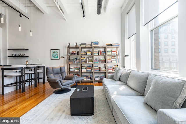 living room featuring beamed ceiling, wood finished floors, and a high ceiling