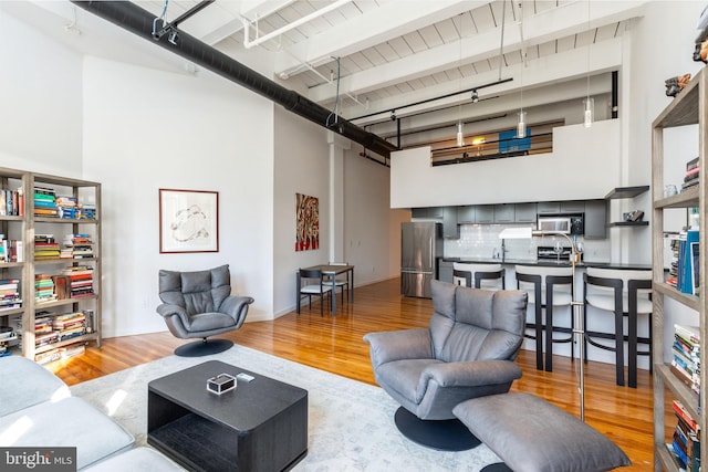 living area featuring track lighting, a towering ceiling, and wood finished floors