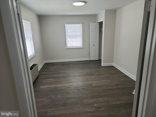 interior space featuring dark wood-style floors, baseboards, and a healthy amount of sunlight