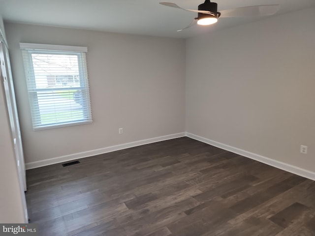 empty room with dark wood finished floors, visible vents, baseboards, and ceiling fan