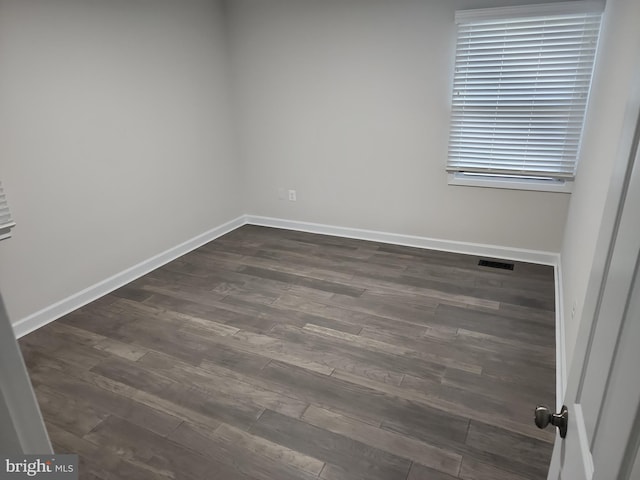 unfurnished room with visible vents, baseboards, and dark wood finished floors