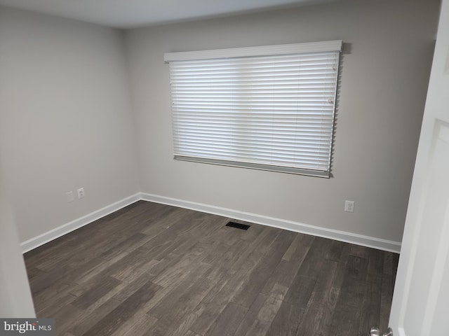 spare room with baseboards, dark wood-style floors, and visible vents