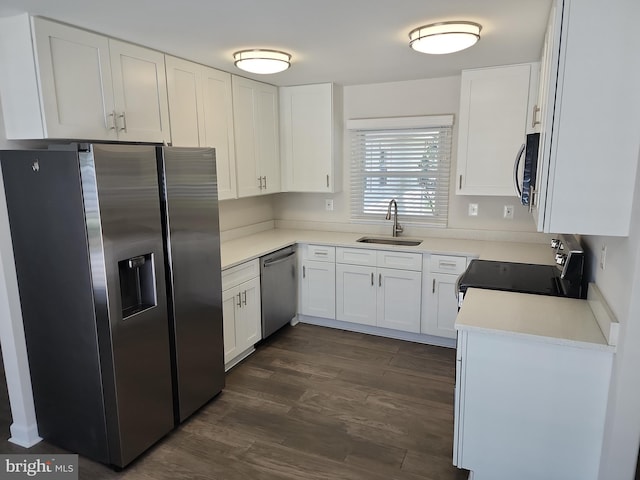 kitchen featuring dark wood-style floors, light countertops, white cabinets, stainless steel appliances, and a sink