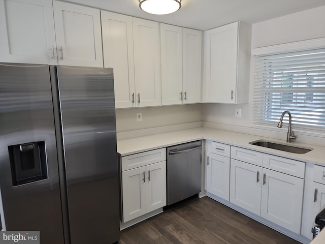 kitchen with stainless steel appliances, white cabinets, a sink, and dark wood finished floors
