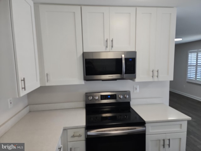 kitchen featuring white cabinets, light countertops, stainless steel microwave, and range with electric stovetop