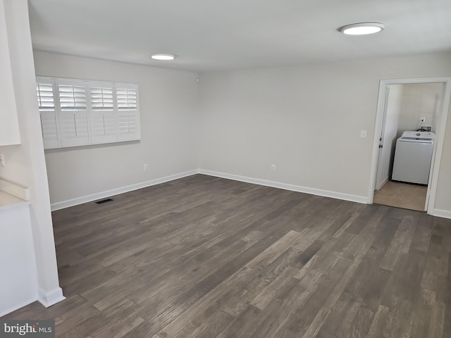 unfurnished room with washer / clothes dryer, baseboards, visible vents, and dark wood finished floors