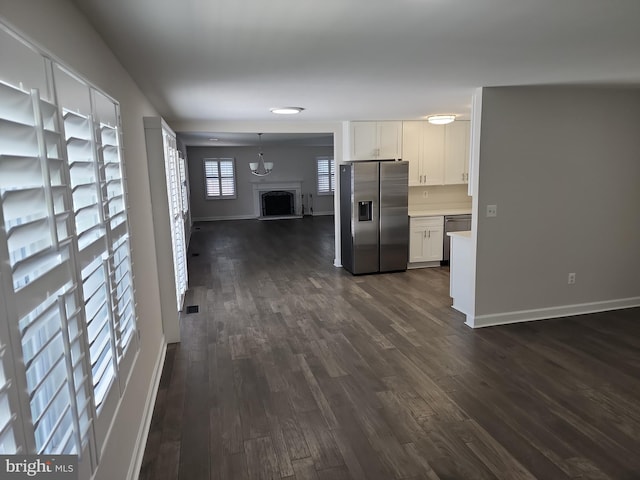 kitchen with open floor plan, light countertops, appliances with stainless steel finishes, dark wood finished floors, and white cabinetry