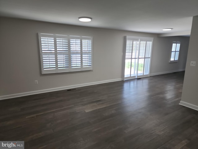 spare room featuring dark wood-style flooring, baseboards, and visible vents