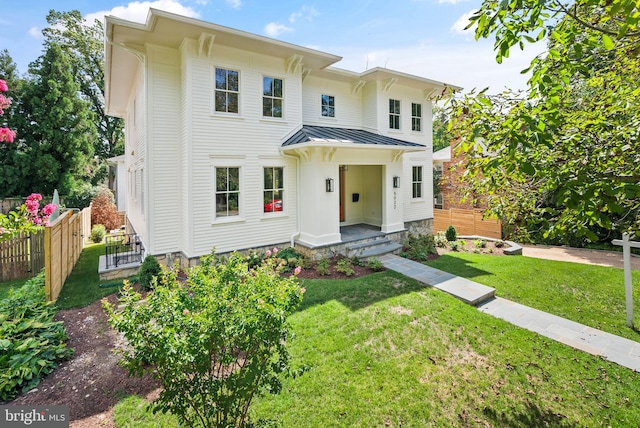 italianate home featuring a standing seam roof, metal roof, fence, and a front lawn