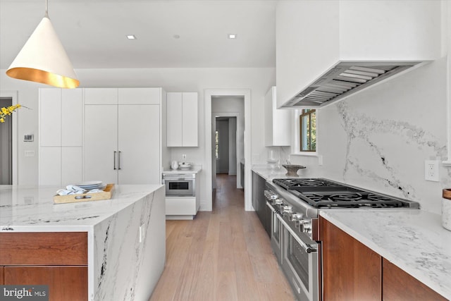 kitchen featuring light wood-style flooring, custom range hood, light stone countertops, high end stove, and white cabinetry