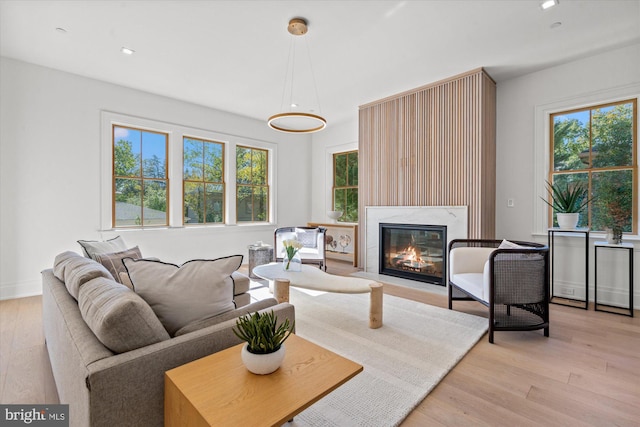 living area featuring baseboards, a premium fireplace, light wood-style flooring, and recessed lighting