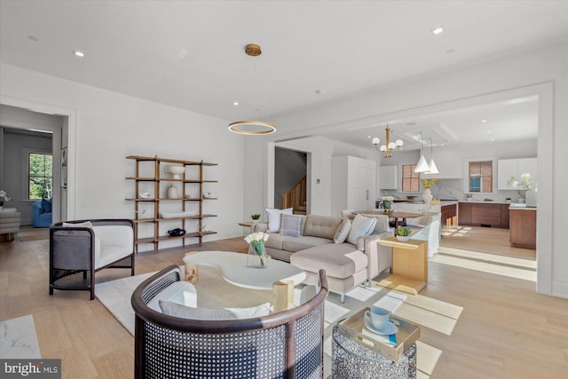 living area featuring stairs, a notable chandelier, light wood-style flooring, and recessed lighting