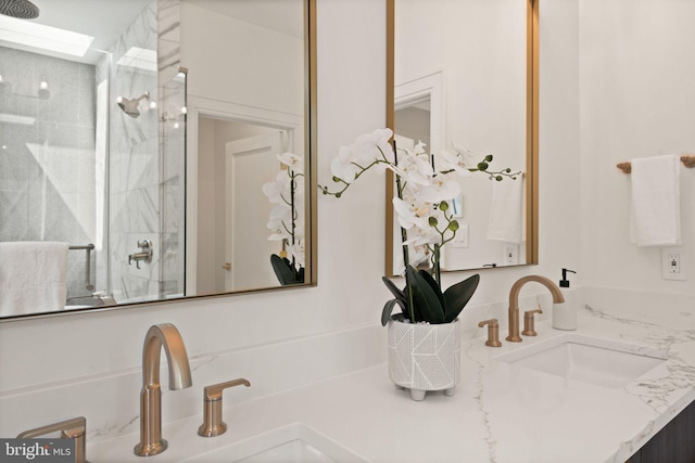 full bathroom with double vanity, a sink, and a marble finish shower