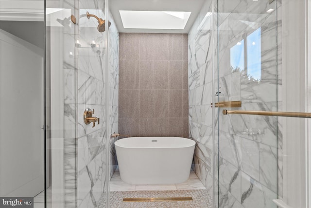 bathroom featuring a skylight, a marble finish shower, and a freestanding tub