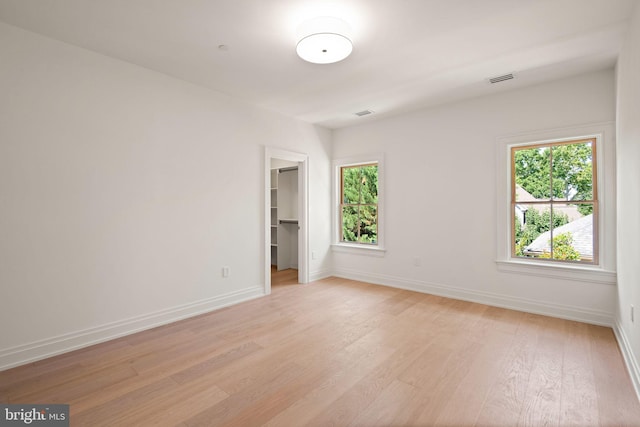 empty room with visible vents, light wood-style flooring, and baseboards