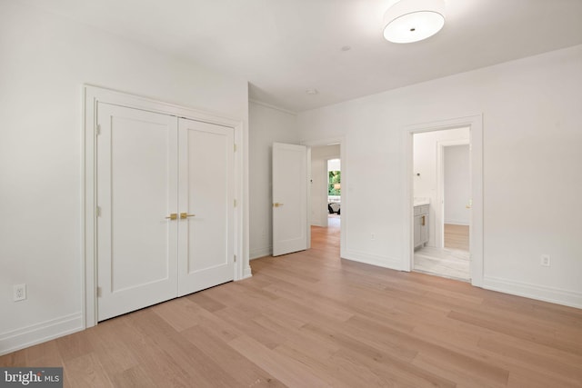 unfurnished bedroom featuring light wood-type flooring, baseboards, a closet, and ensuite bathroom