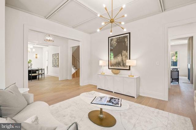 living room with a chandelier, light wood-type flooring, baseboards, and stairs