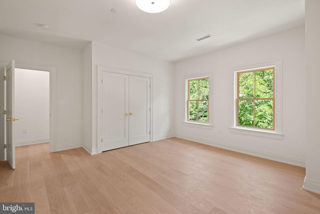 unfurnished bedroom featuring baseboards, visible vents, and light wood-style floors