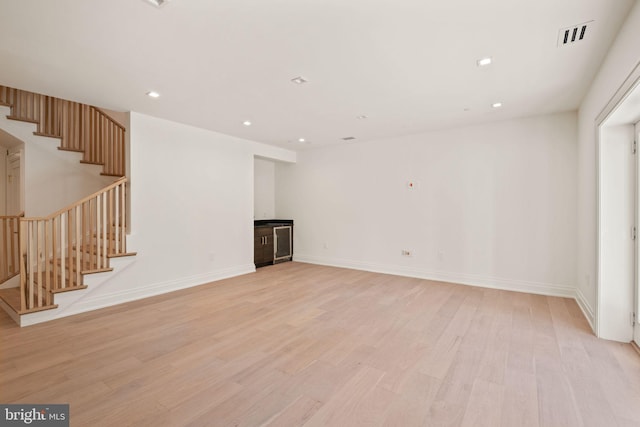 unfurnished living room featuring light wood finished floors, stairs, and recessed lighting