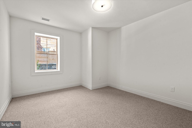 unfurnished room with baseboards, visible vents, and light colored carpet