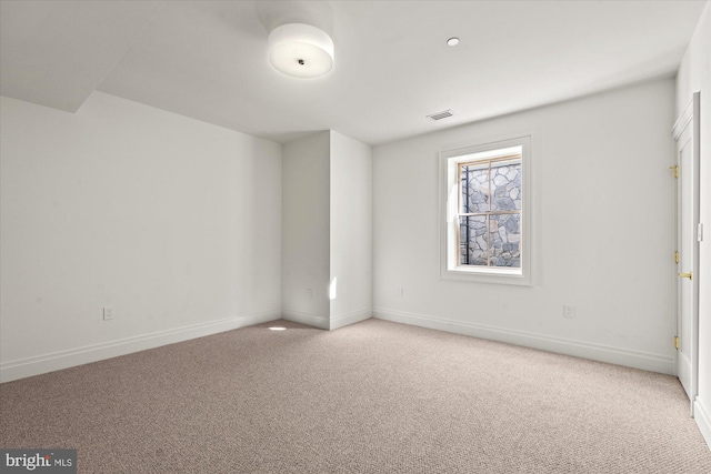 unfurnished room with light carpet, visible vents, and baseboards