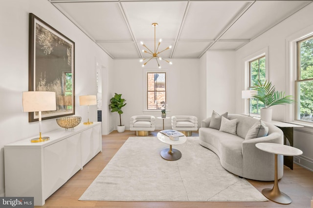 living area featuring a wealth of natural light, a notable chandelier, and light wood-style flooring