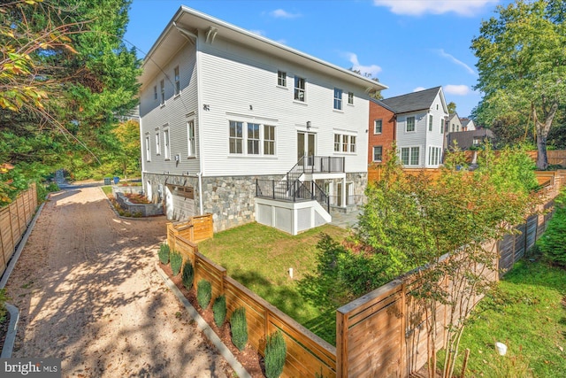 rear view of house with dirt driveway and fence