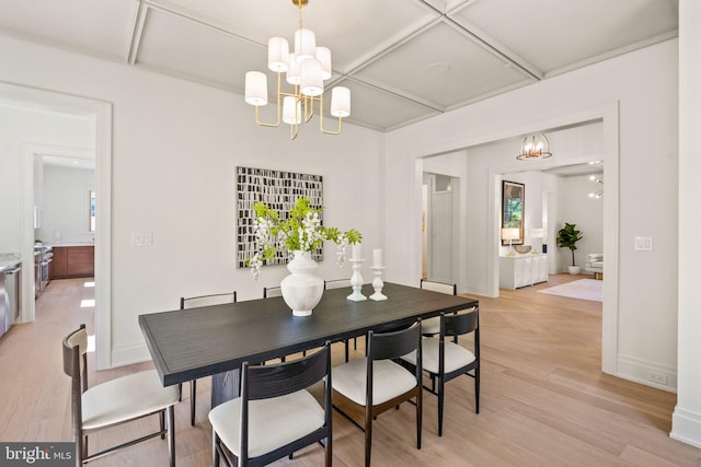 dining space featuring light wood-style flooring, baseboards, coffered ceiling, and a notable chandelier