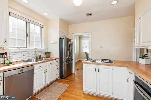 kitchen featuring a sink, visible vents, appliances with stainless steel finishes, and white cabinetry