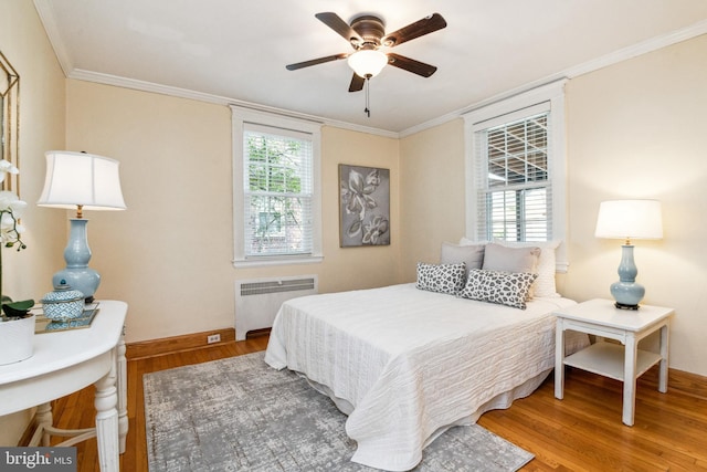 bedroom featuring radiator, wood finished floors, baseboards, and ornamental molding