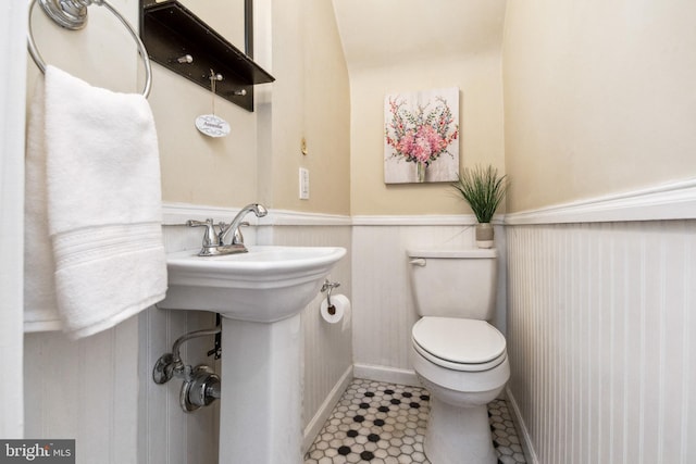 half bathroom with toilet and a wainscoted wall