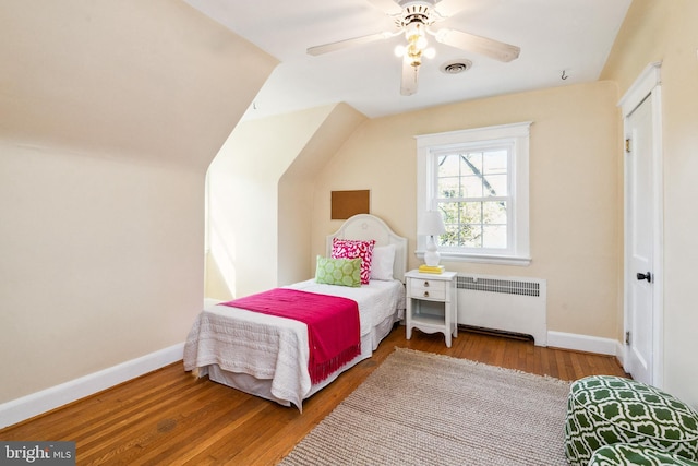 bedroom featuring visible vents, radiator, baseboards, and wood finished floors