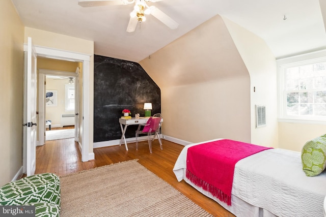 bedroom with vaulted ceiling, visible vents, baseboards, and wood finished floors