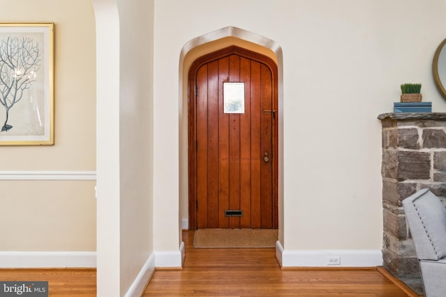 entryway featuring baseboards, arched walkways, and wood finished floors