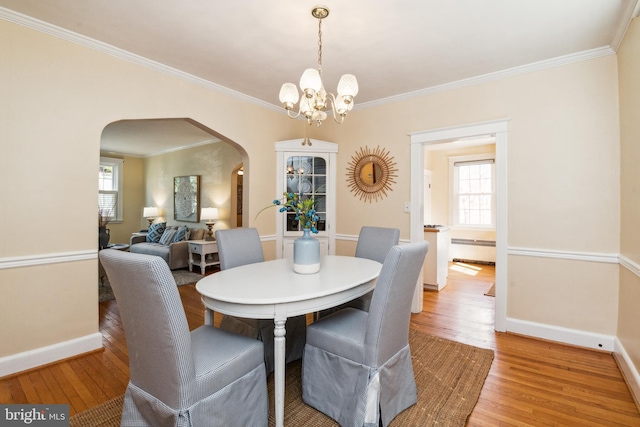 dining room featuring plenty of natural light, light wood-style floors, and arched walkways