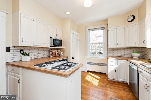 kitchen featuring white gas cooktop, white cabinetry, radiator heating unit, built in microwave, and dishwasher