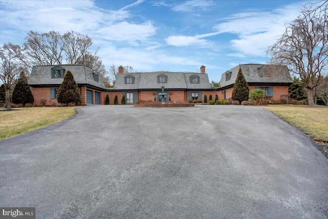 view of front of home featuring a garage, a front yard, aphalt driveway, and brick siding