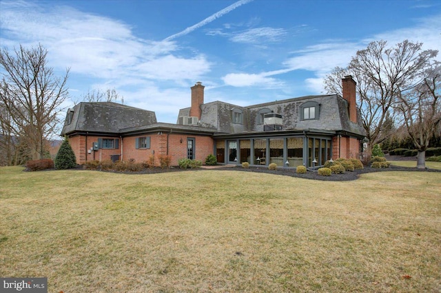 back of house with a chimney, mansard roof, a lawn, and brick siding