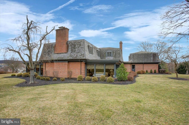 back of house with brick siding, a lawn, a chimney, and mansard roof