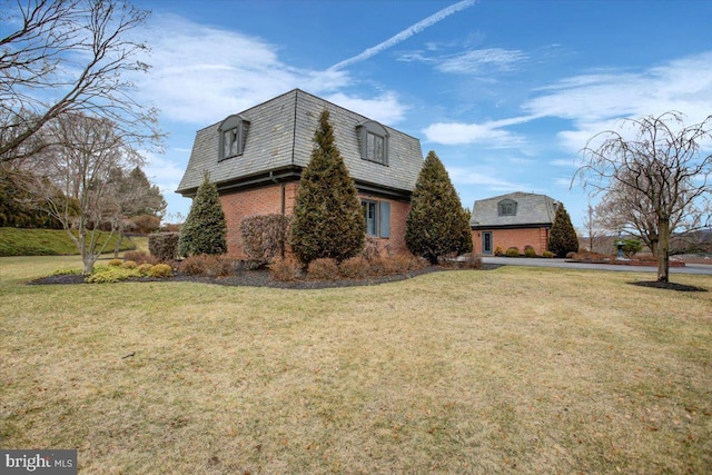 view of home's exterior with a high end roof, mansard roof, a lawn, and brick siding