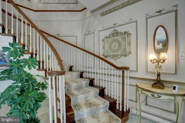 stairway with a baseboard heating unit, an inviting chandelier, and crown molding