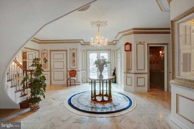 entrance foyer featuring a decorative wall, a notable chandelier, marble finish floor, ornamental molding, and stairway