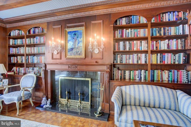 sitting room with built in shelves, a premium fireplace, and crown molding