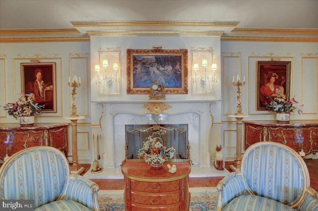 living area featuring a fireplace with raised hearth and crown molding