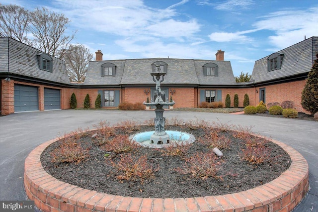 exterior space featuring a high end roof, driveway, and a chimney