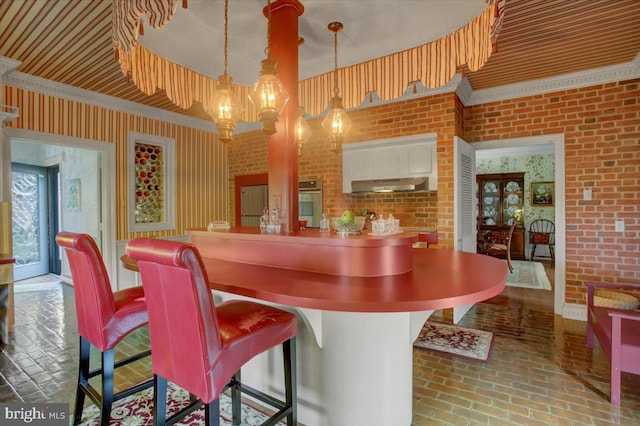 bar featuring brick floor, oven, under cabinet range hood, and brick wall